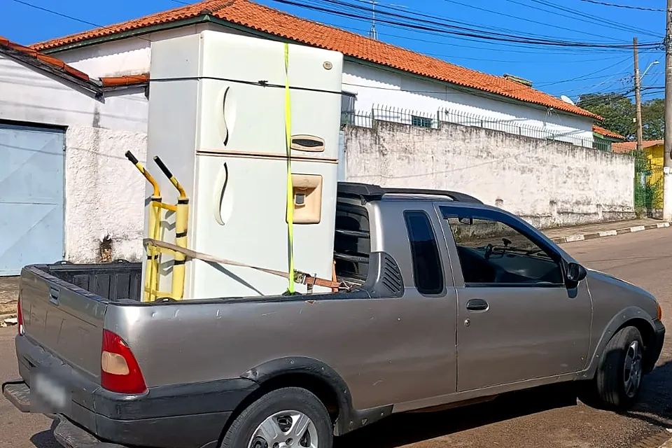 Caminhonete da Nando Máquinas levando uma geladeira amarrada na caçamba
