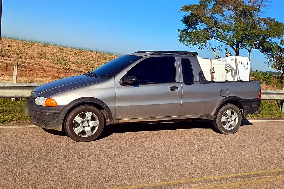Caminhonete com máquinas de lavar numa estrada perto de um canavial